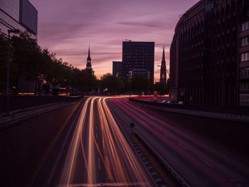 Light trails on road against sky at dusk