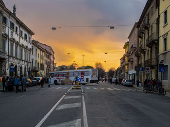 Cars on road in city against sky at sunset