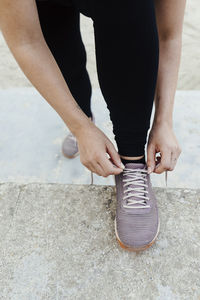 Close up of young woman's hands tying her shoes before sport.