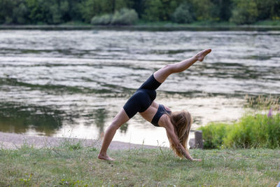 Full length of young woman jumping on field