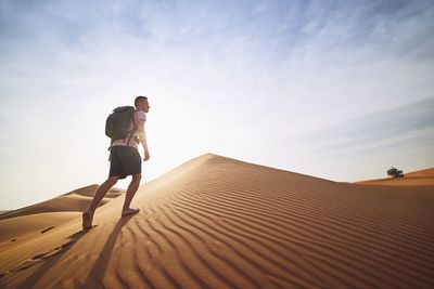 Full length of man on sand dune in desert against sky