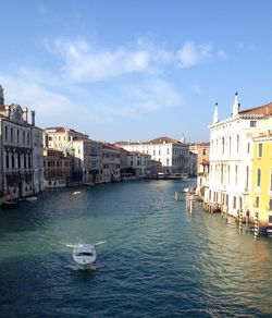 Boats in canal amidst buildings in city against sky