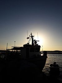 Silhouette boats moored in sea against clear sky during sunset