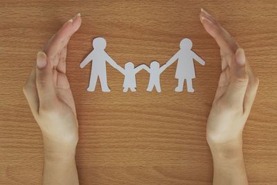 Directly above shot of human hands with paper cutouts on table