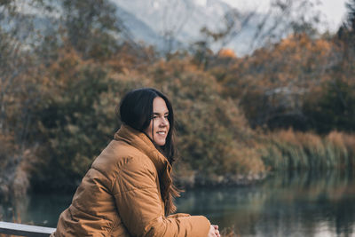 Young woman standing on shore of lake in autumn