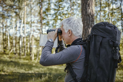 Midsection of man holding camera while standing on land