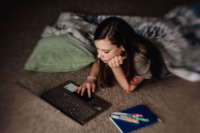 Young woman using mobile phone while sitting on bed at home