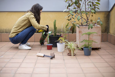 Woman with potted plants on tiled floor