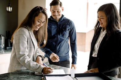 Couple signing contract with realtor at kitchen island of new house