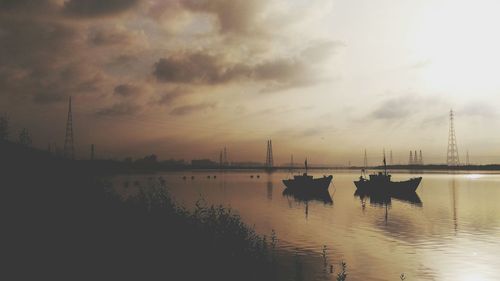 Silhouette of boats in lake during sunset