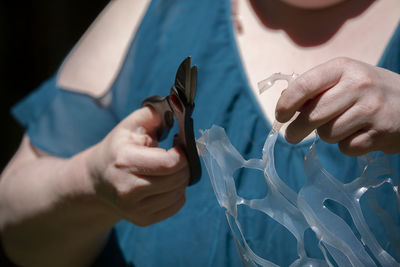 Midsection of woman cutting plastic with scissors