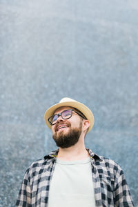 Happy man wearing hat standing against wall