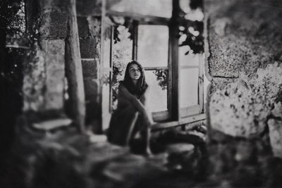 Portrait of young woman looking through window