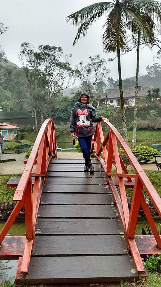 PORTRAIT OF WOMAN STANDING ON FOOTBRIDGE AGAINST SKY