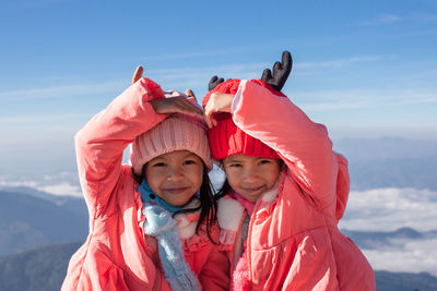 Portrait of cute siblings wearing warm clothing against sky