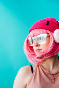 Bright extravagant appearance. portrait of a girl with a short pink haircut on a blue background.