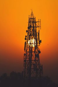 Silhouette crane against orange sky