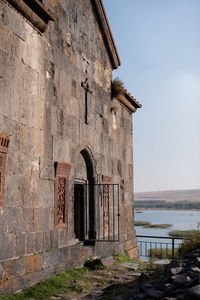 Old ruins on the mountain by lake against sky