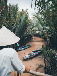 People in boat against palm trees