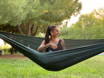 Woman smiling while sitting on grass against trees