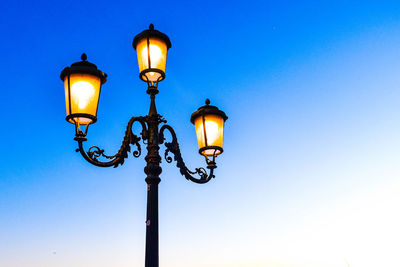 Low angle view of street light against blue sky