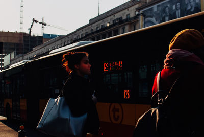 Rear view of woman standing on bus in city