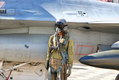 Pilot standing against military airplane
