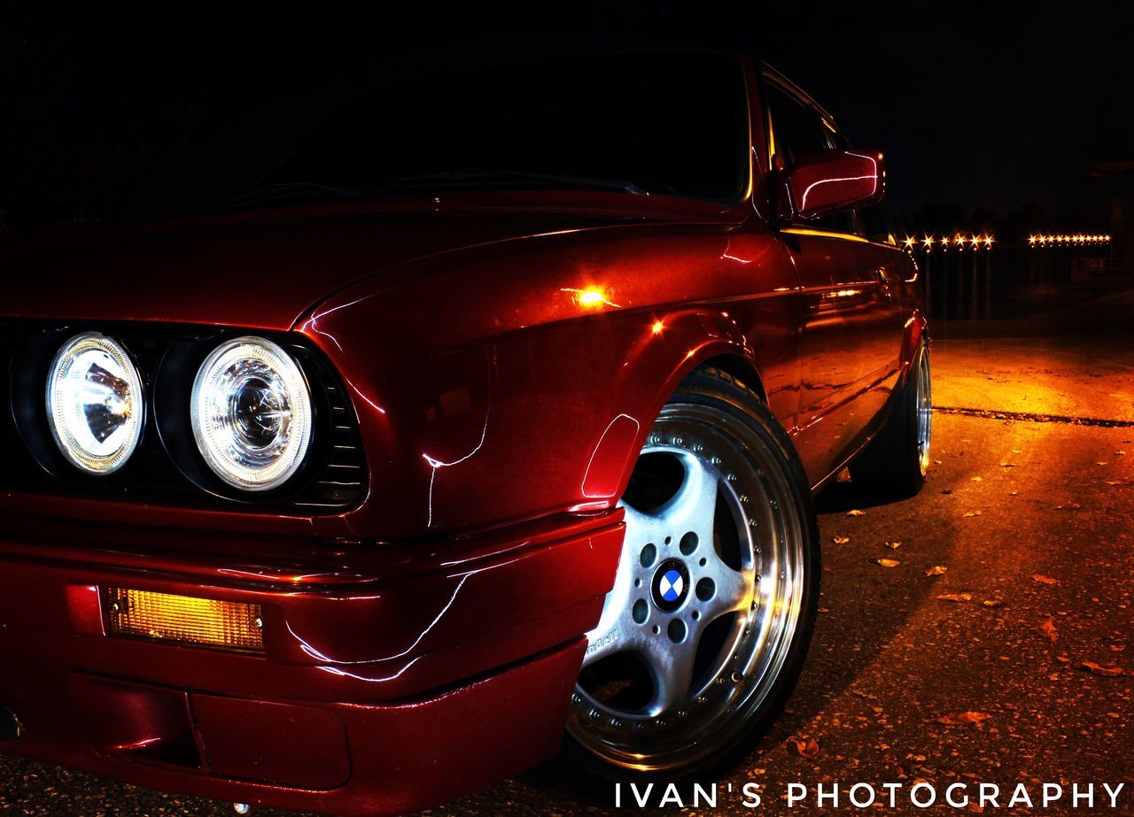 CLOSE-UP OF VINTAGE CAR ON CITY AT NIGHT