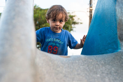 Low angle portrait of boy playing on slide at playground