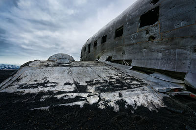 Crashed airplane on beach at solheimasandur against cloudy sky