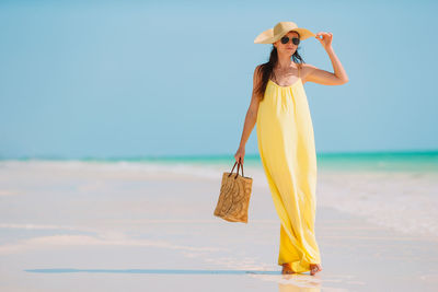 Woman with umbrella standing on beach