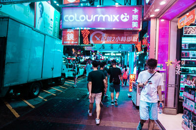 Rear view of people walking in illuminated city at night