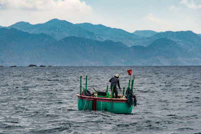 Fishing boat sailing in sea against sky