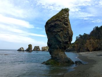 Rock formation on beach against sky