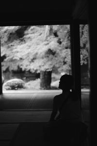 Rear view of man sitting in window