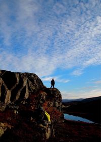Woman standing on rock formation against sky