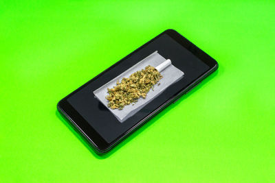 High angle view of smart phone on green background