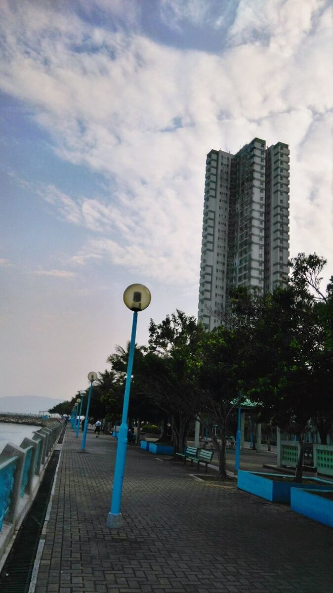 building exterior, sky, built structure, architecture, city, street light, cloud - sky, tree, cloud, tall - high, modern, skyscraper, railing, office building, outdoors, cloudy, day, street, tower, the way forward