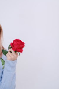 Rear view of woman holding flower against white background