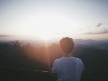 Rear view of man looking sun in sky during sunrise