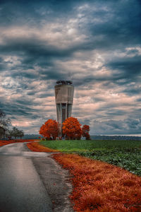 Road amidst field against sky during sunset