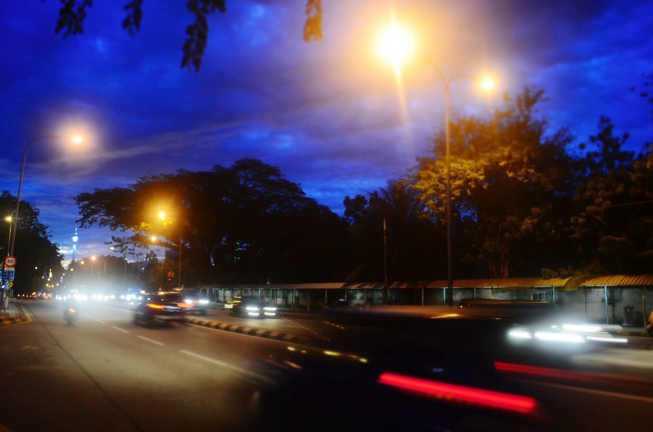 illuminated, night, transportation, road, long exposure, light trail, sky, street light, car, street, tree, motion, land vehicle, road marking, speed, city, dusk, blurred motion, traffic, building exterior