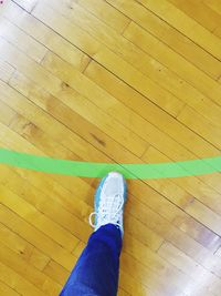 Low section of person standing on hardwood floor