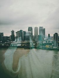 River amidst buildings in city against sky