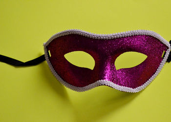Close-up of pink mask on yellow background