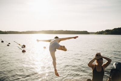 Shirtless man diving from jetty at lake against sky in summer
