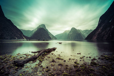 Scenic view of lake and mountains against cloudy sky