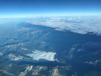 Aerial view of sea and mountains against blue sky