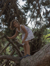 Woman standing by tree trunk in forest