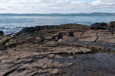 Rock formation on beach against sky